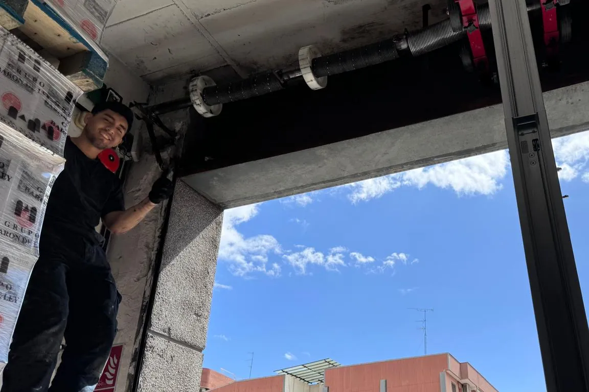 Instalador montando el eje y los muelles de una puerta enrollable